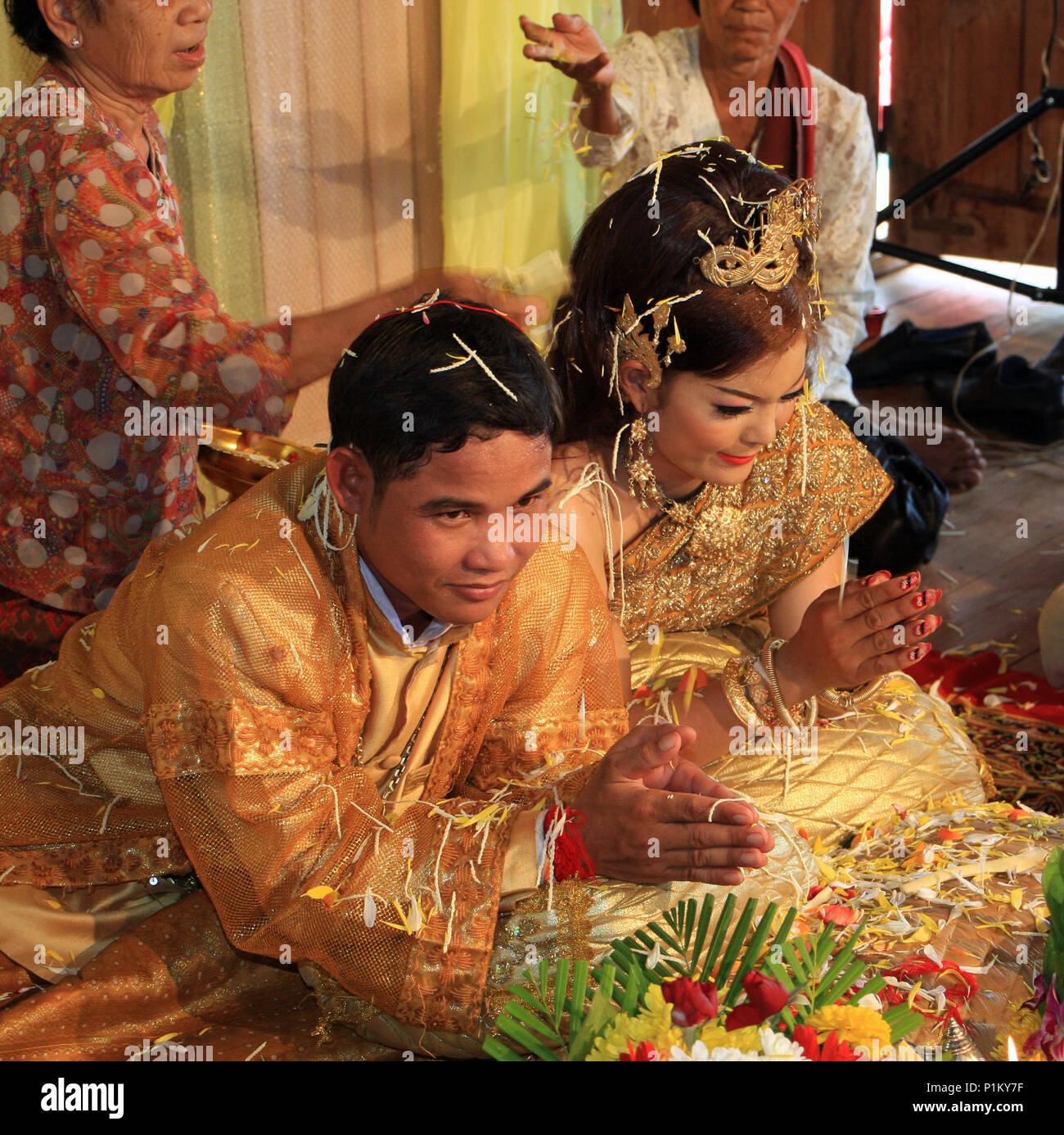 Nahe dem Ende des kambodschanischen Hochzeit die Großmütter werfen Blütenblätter über die kniende Paar. Stockfoto