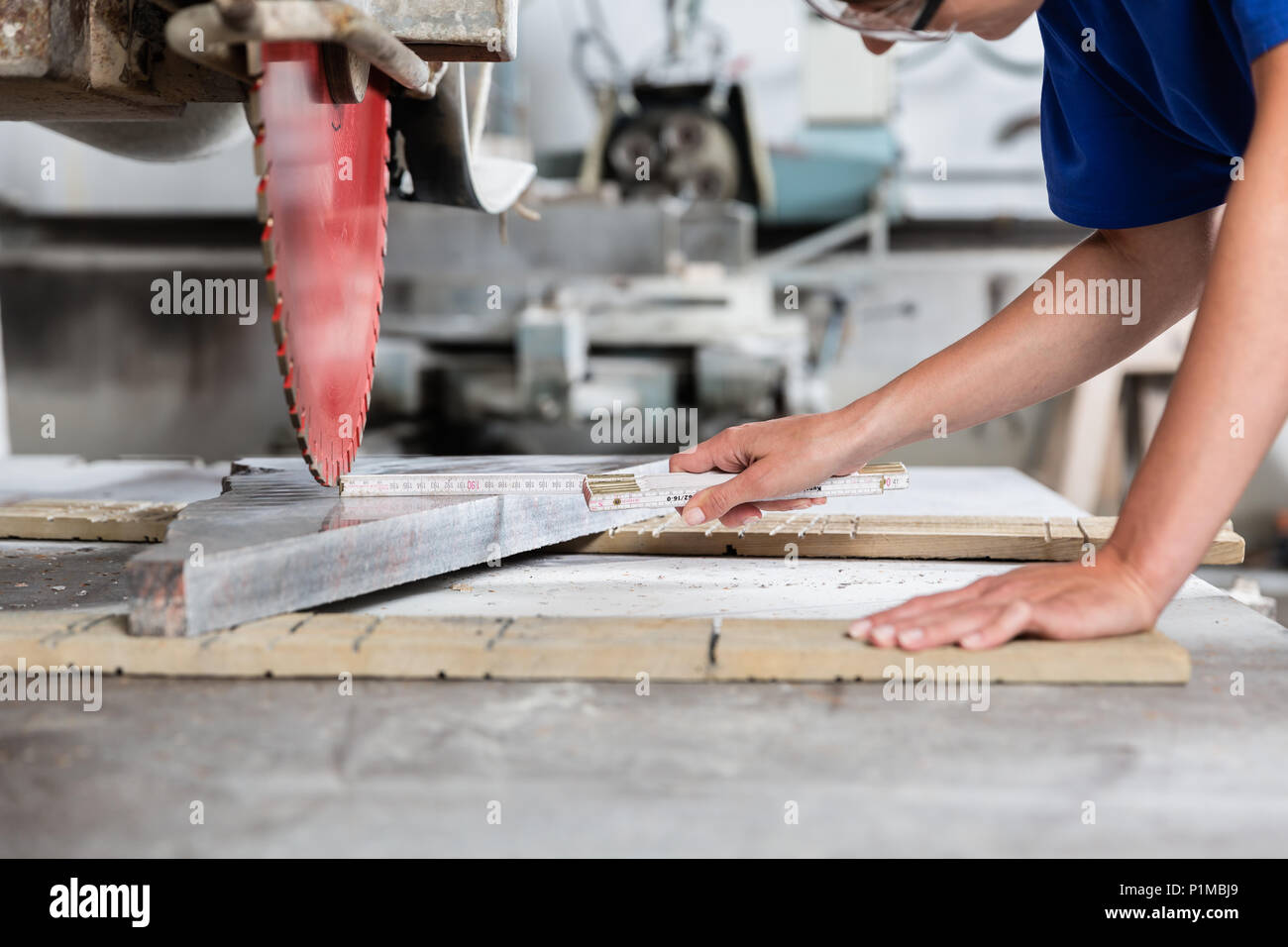 Steinmetz Frau messen Steinplatte zum Sägen in der Werkstatt Stockfoto
