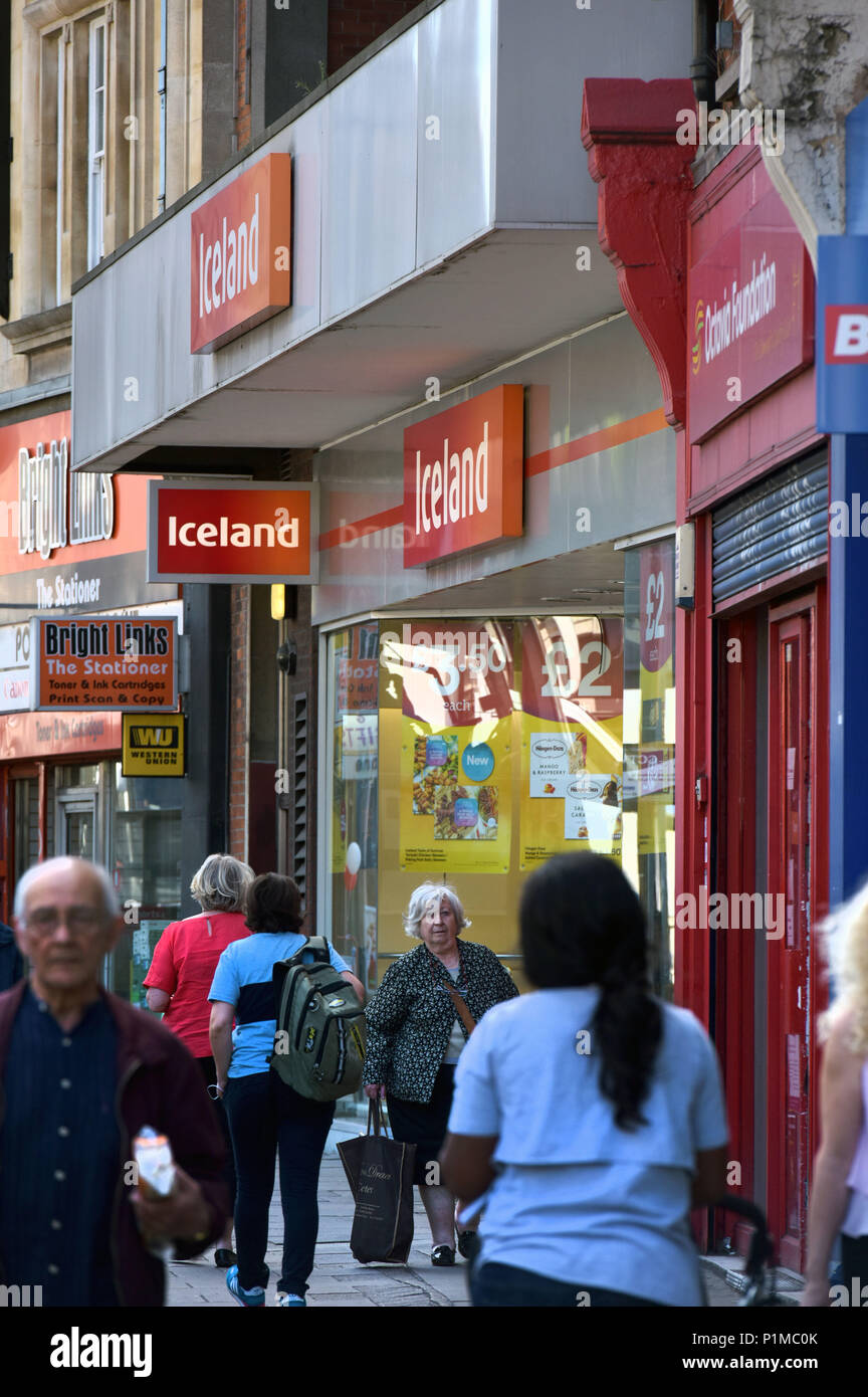 Menschen und Käufer vorbei unabhängig und Läden von Wohltätigkeitsorganisationen und eine Filiale von Island, auf die Finchley Road High Street im Norden von London entfernt. Stockfoto