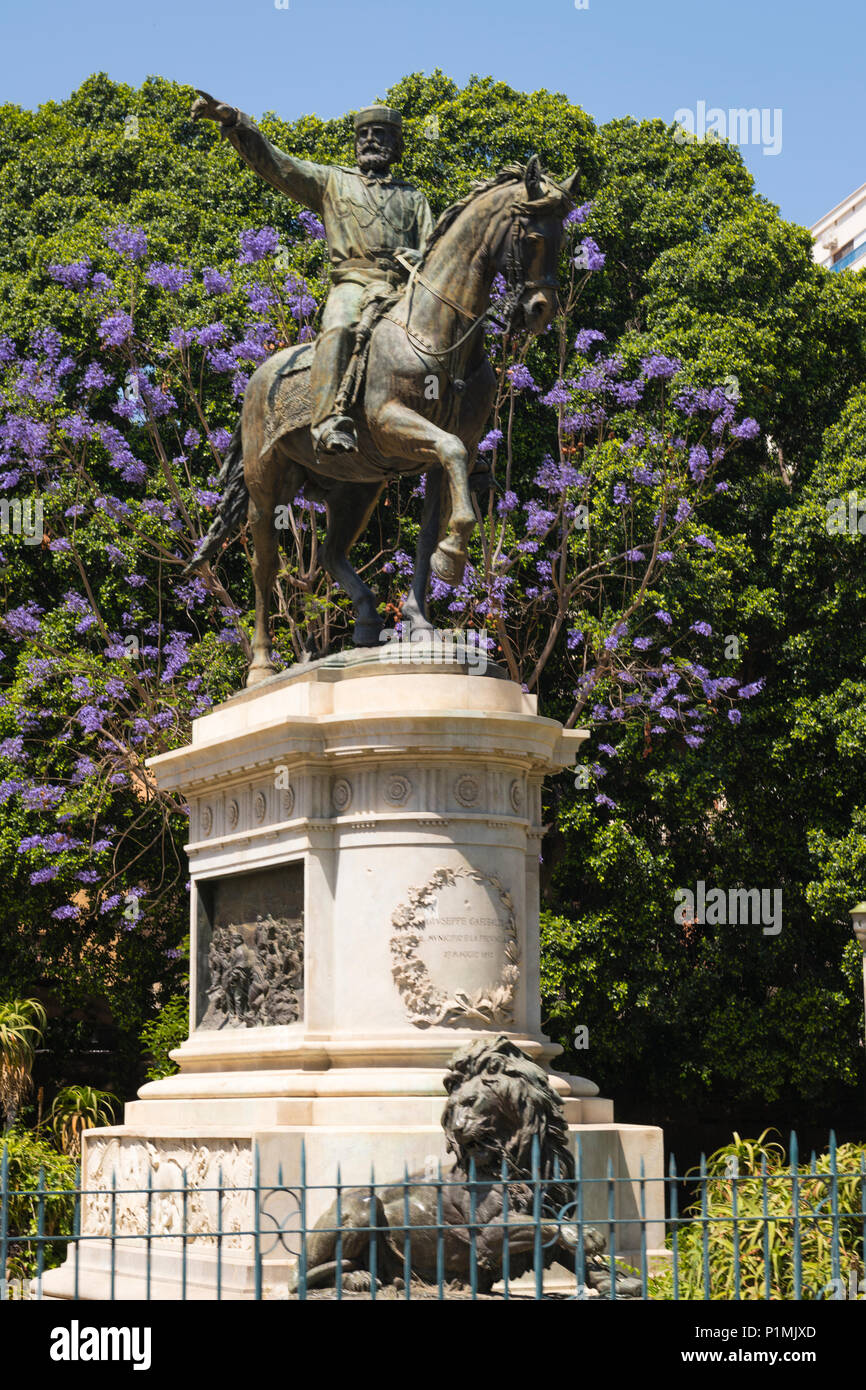 Italien Sizilien Palermo Bronze Statue Skulptur Löwe Giuseppe Garibaldi reiten Pferd auf Sockel Baum Bäume Geländer blau blühende Stockfoto