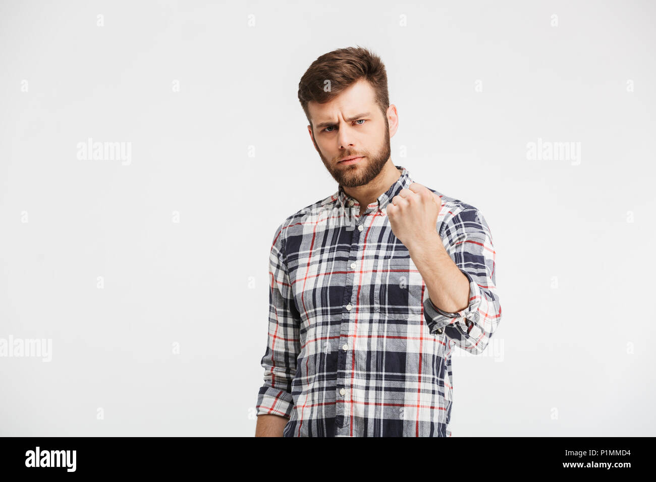 Porträt eines zornigen jungen Mann droht mit einer Faust auf weißem Hintergrund Stockfoto