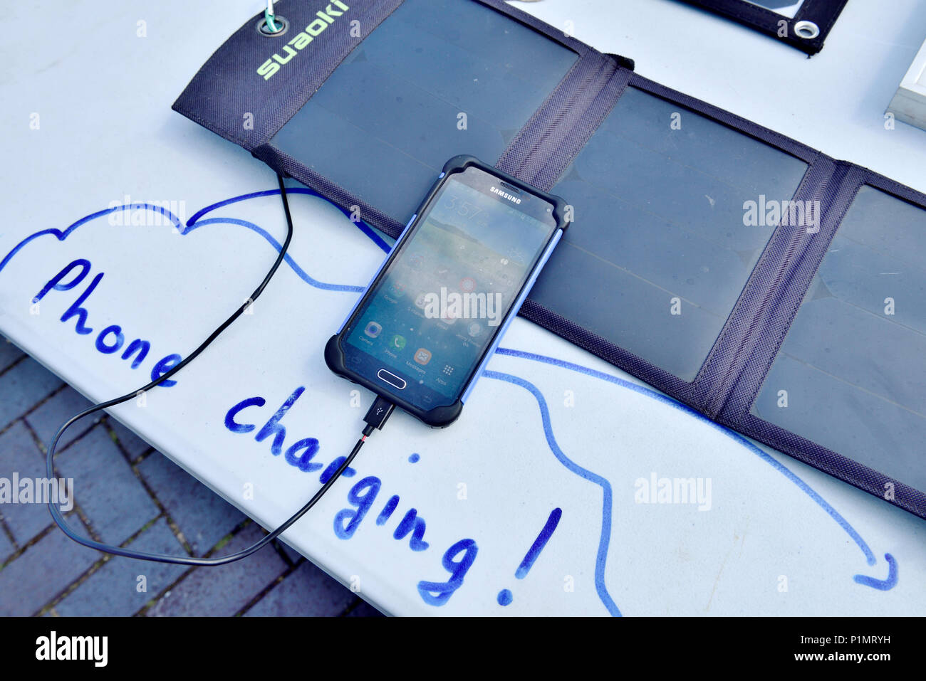Demonstration der kleine tragbare Solar Panel pack Aufladen eines Mobiltelefons Stockfoto