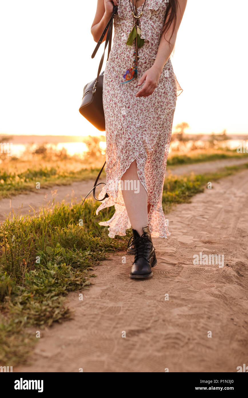 7/8-Foto von stilvollen kaukasische Frau in Kleid zu Fuß auf der Straße in die Landschaft während der sonnigen Sommertag Stockfoto