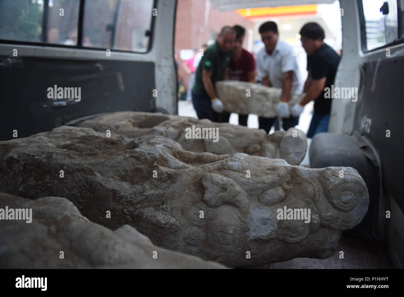 (180613) - Peking, 13. Juni 2018 (Xinhua) - Arbeitnehmer last Staats Marmor Drachen auf einen Van in der Kleinstadt der Qinghe, Haidian, Peking, Hauptstadt von China, 12. Juni 2018. Vier Köpfe von Marmor Drachen, ausgegraben von einer Baustelle, zu den Alten Sommerpalast Yuanmingyuan zurückgegeben wurden, auch am Dienstag aufgerufen. Sie wurden als Reliquien des Yuanmingyuan von Experten identifiziert, Dank der Bericht von Du Zening, ein normaler Bürger. (Xinhua / xiaoguang Luo) (lb) Stockfoto