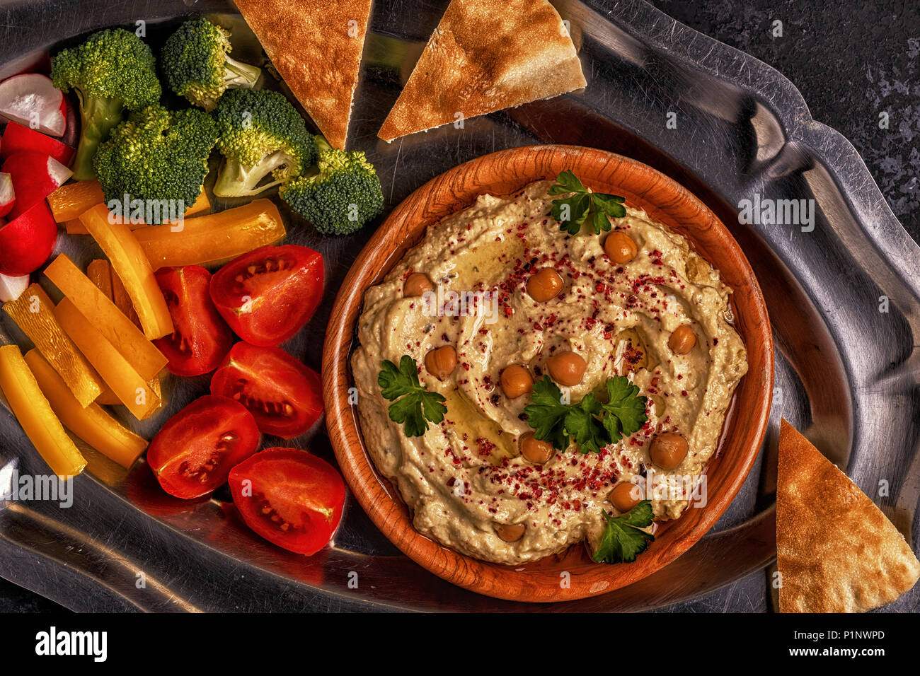 Klassische Hummus mit Gemüse auf dem Teller und Fladenbrot. Stockfoto