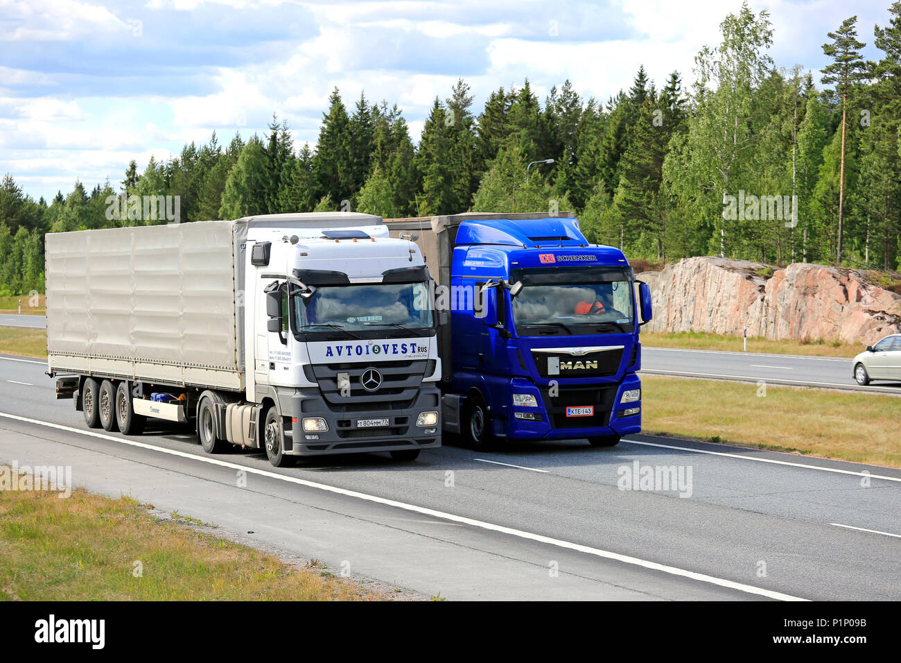 Blue Man halb Lkw überholt einen Lkw auf der Autobahn im Sommer. Lkw mit schwerer Ladung kann viel langsamer bergauf. Salo, Finnland - 8. Juni 2018. Stockfoto