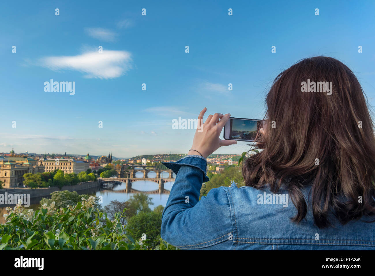 Brünette Frau, von hinten, die Bilder mit Ihrem Smartphone mit der Moldau, die Brücken und die Hauptstadt Prag, in der Tschechischen Republik. Stockfoto