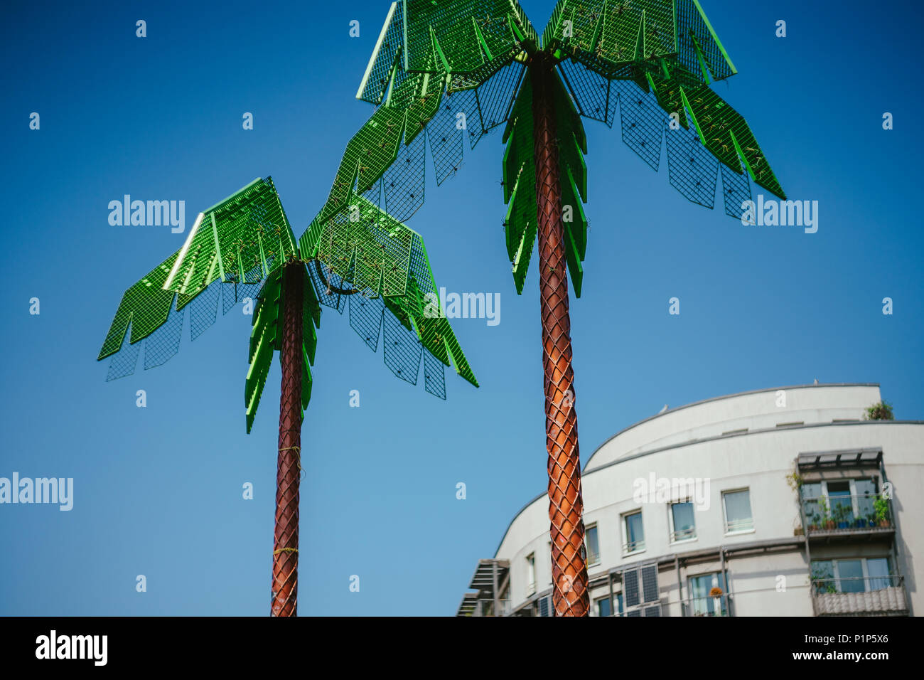 Künstliche grün Metall Palmen mit weißen Wohnhaus und blauer Himmel im Park Fiction Hamburg. Eine künstlerische und gesellschaftspolitische Projekt im kleinen Park in der Nähe von St. Pauli, Hamburg Stockfoto
