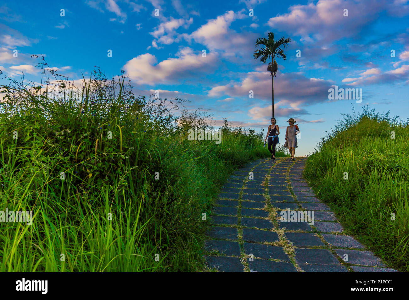 Zwei Frauen gehen die Campuhan Ridge Spaziergang in der Morgendämmerung, eine gepflasterte Weg über den Hügeln außerhalb von Ubud, Bali, Indonesien, 15. April 2018 Stockfoto