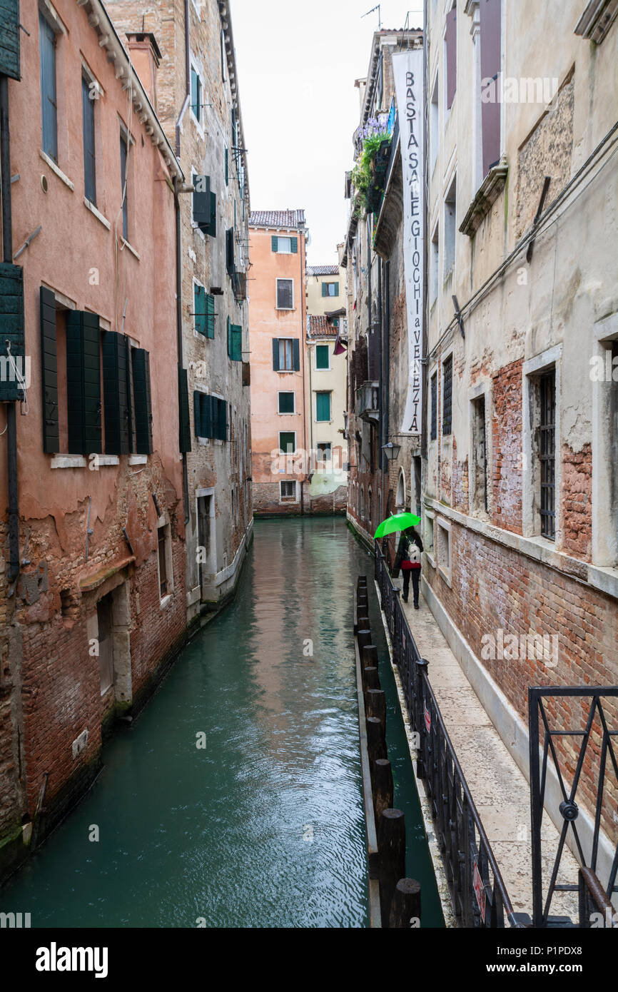 Backwaters von Venedig einschließlich Frau mit leuchtend grünen Regenschirm Stockfoto