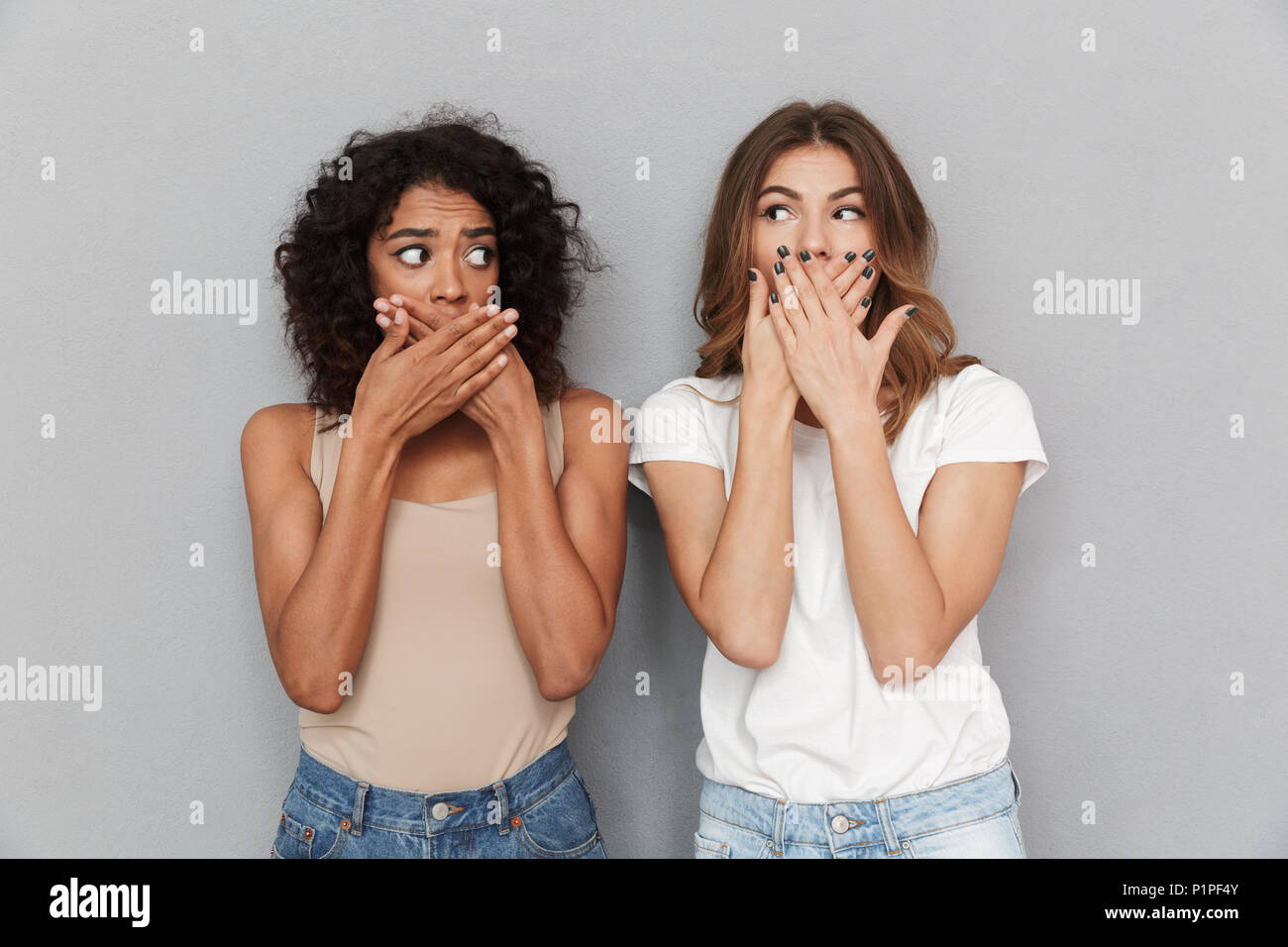 Porträt von zwei schockiert Frauen, Mund über grauer Hintergrund Stockfoto