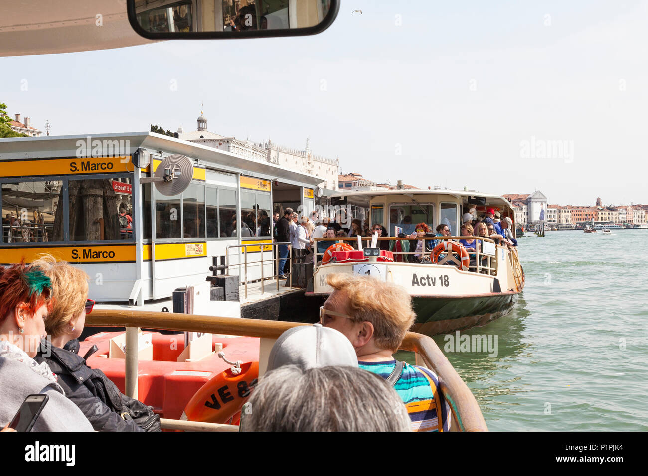 Reisen mit überfüllten Vaporetto Wasserbus in Venedig, Venetien, Italien mit Massen von Menschen Einsteigen in ein Boot an der Haltestelle San Marco in der ersten Person P Stockfoto