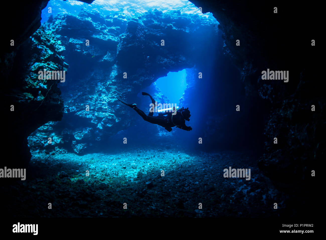 Scuba Diver schwimmt durch Lava Bögen mit Sonnenstrahlen, Kathedralen Tauchplatz; Lanai City, Lanai, Hawaii, Vereinigte Staaten von Amerika Stockfoto