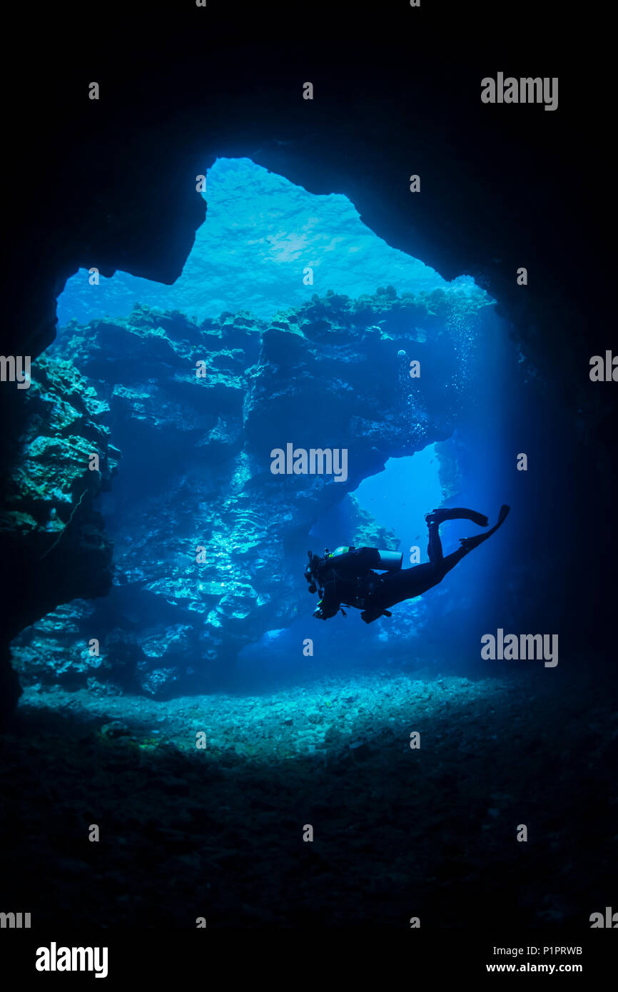 Scuba Diver schwimmt durch Lava Bögen mit Sonnenstrahlen, Kathedralen Tauchplatz; Lanai City, Lanai, Hawaii, Vereinigte Staaten von Amerika Stockfoto