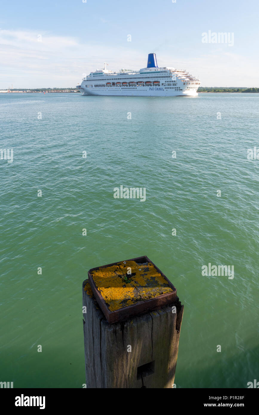 Die p und o Kreuzfahrtschiffes oriana verlassen den Hafen von Southampton auf einer Kreuzfahrt in wärmeren Gewässern mit einer alten hölzernen Pfosten in den Vordergrund Perspektive zu geben Stockfoto