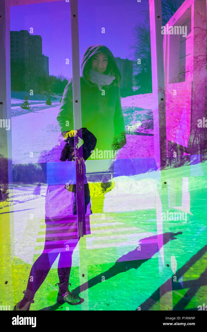 Eine Frau macht ein Foto von Ihrem Freund durch die neon Plexiglas von einem Wärmenden Hütte Kunst Struktur entlang des Roten Flusses gegenseitige Trail Stockfoto
