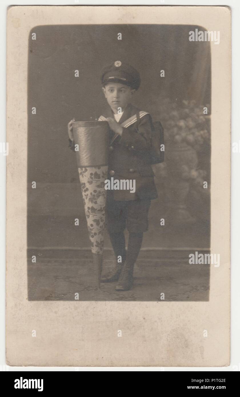 WALDENBURG, Deutschland - circa 1920s: Vintage Foto zeigt kleine Junge mit einer Schule Kegel (Tute"), einen großen Karton Kegel mit Spielzeug, Schokolade, Bonbons, angesichts der erste Tag in der Schule. Retro black & white Studio. Stockfoto