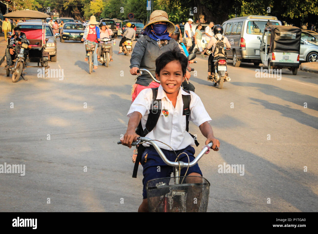 Siem Reap, Kambodscha - Januar 2014: Glücklich lächelnde School Zicklein auf dem Fahrrad im Straßenverkehr in Siem Reap, Kambodscha Stockfoto