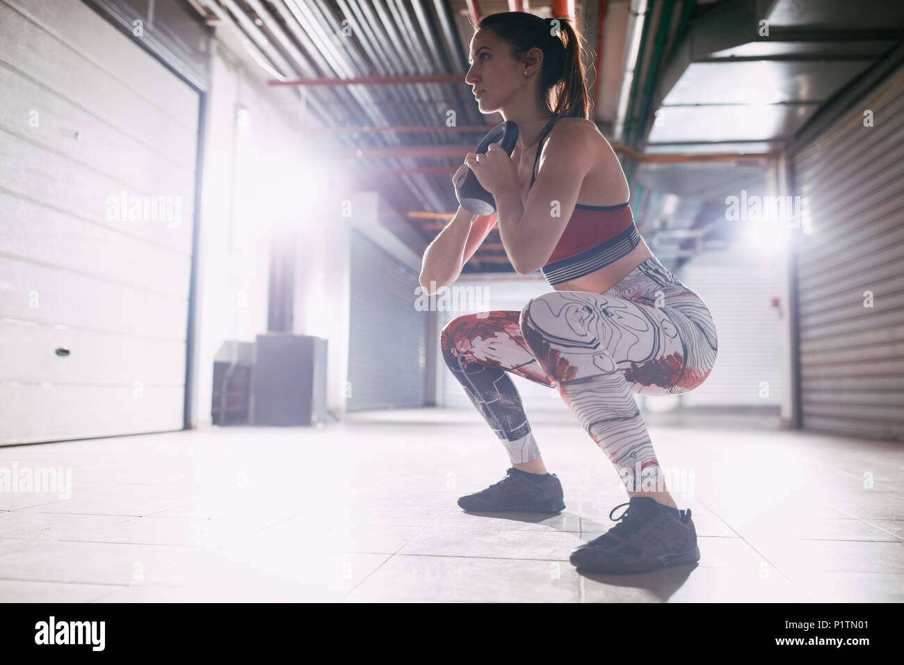 Junge muskulöse Frau übung Goblet Squat mit kettlebell auf hartes Training in der garage Gym. Stockfoto