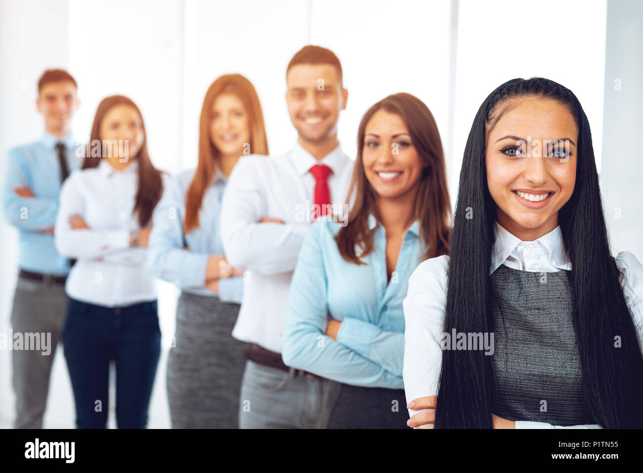 Lächelnd Gruppe junger Geschäftsleute Stehen mit verschränkten Armen und lookingat Kamera. Stockfoto