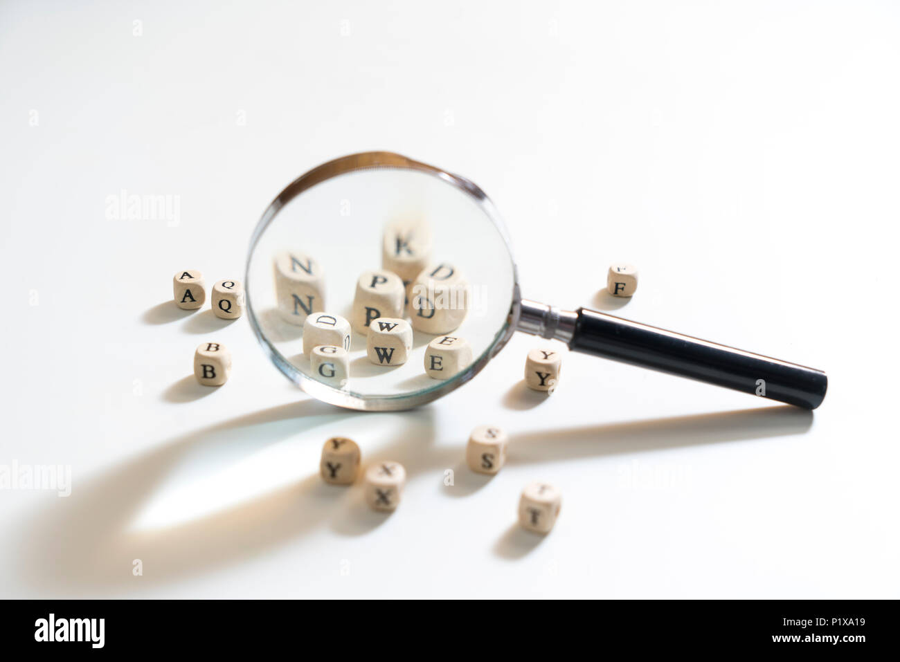 Eine Lupe zwischen einige Buchstaben des Alphabets auf eine weiße Fläche Stockfoto