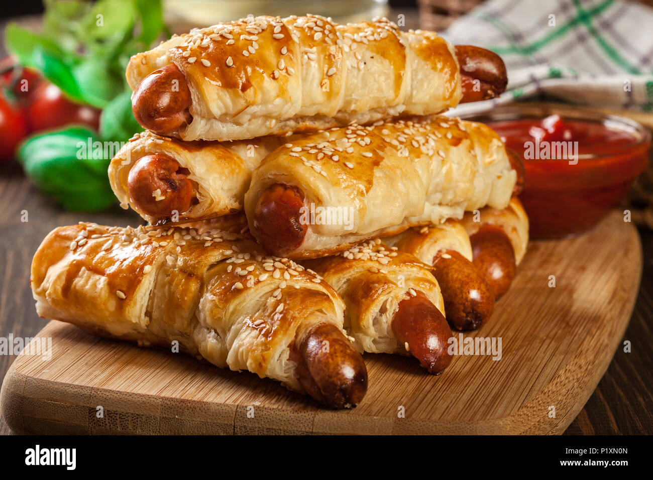 Hot Dog Würstchen in Blätterteig gebacken auf einem Schneidebrett gerollt Stockfoto