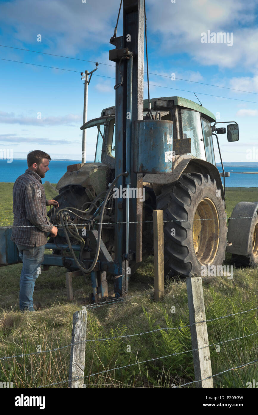 dh Posts Zaun Rammmaschine LANDWIRTSCHAFT Großbritannien Traktor Feldmaschinen Landwirt Betrieb nach hydraulischem Stampfer Barbwire Fechten Farmarbeiter Menschen Bauernhof Stockfoto