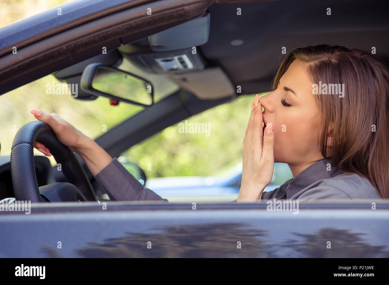 Seitenansicht des Jungen casual Frau Gähnen und müde, während im Auto sitzen und Fahren im Tageslicht. Stockfoto