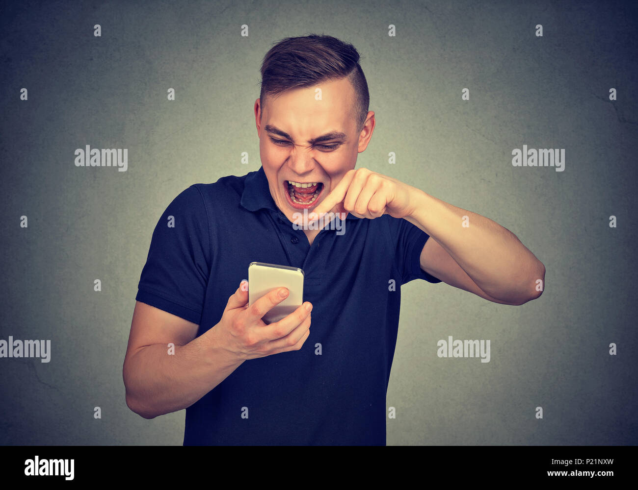 Porträt zorniger junger Mann schreien am Handy auf graue Wand Hintergrund isoliert. Negative Emotionen Gefühle Stockfoto