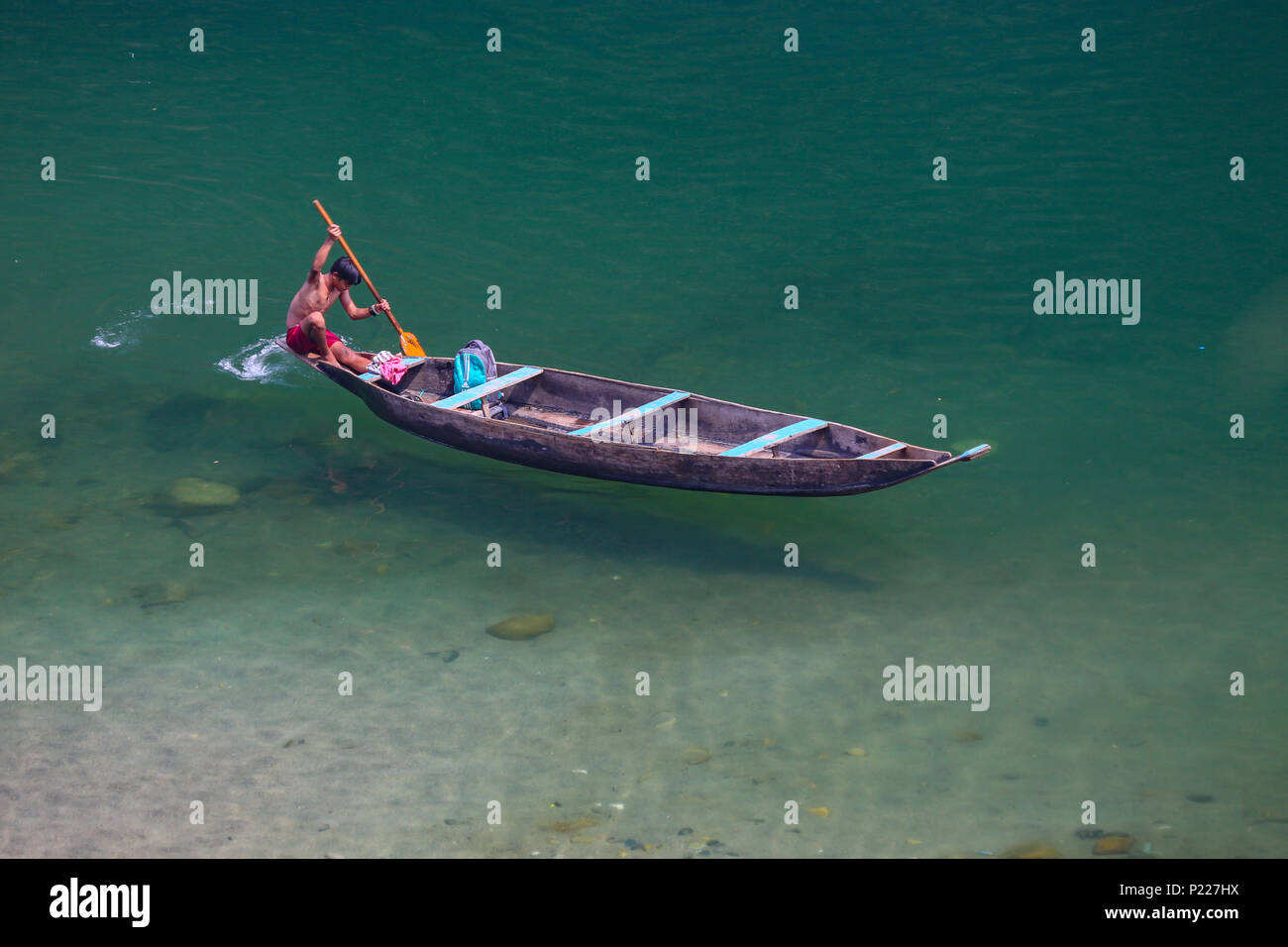 Ein lokaler Junge Zeilen das Boot in Umngot River bei Dawki (meghalaya) Stockfoto