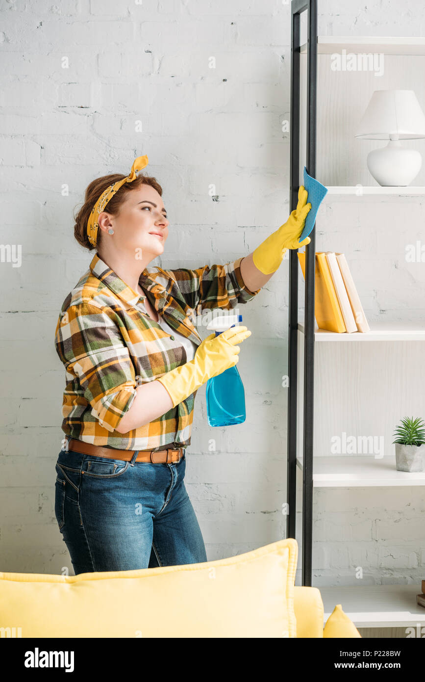 Schöne Frau abstauben Regale zu Hause Stockfoto