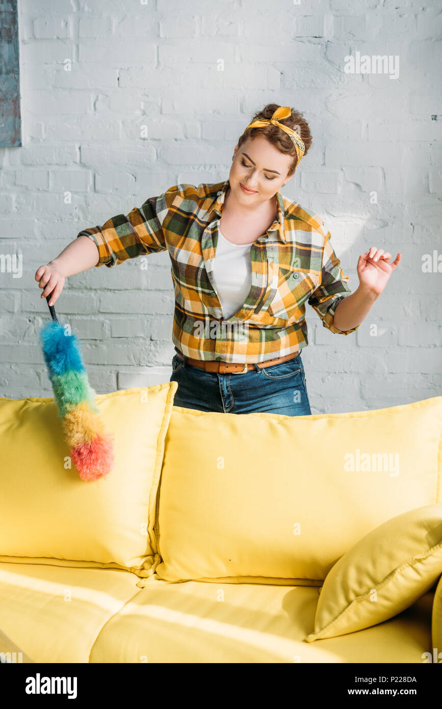 Schöne Frau abstauben gelb Sofa zu Hause Stockfoto