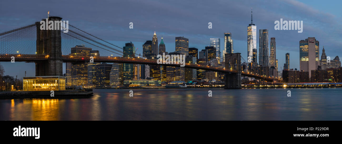 Panoramablick auf die lange Exposition der Brooklyn Bridge und die Skyline von Manhattan in der Morgendämmerung über dem East River in Brooklyn, New York, USA Stockfoto