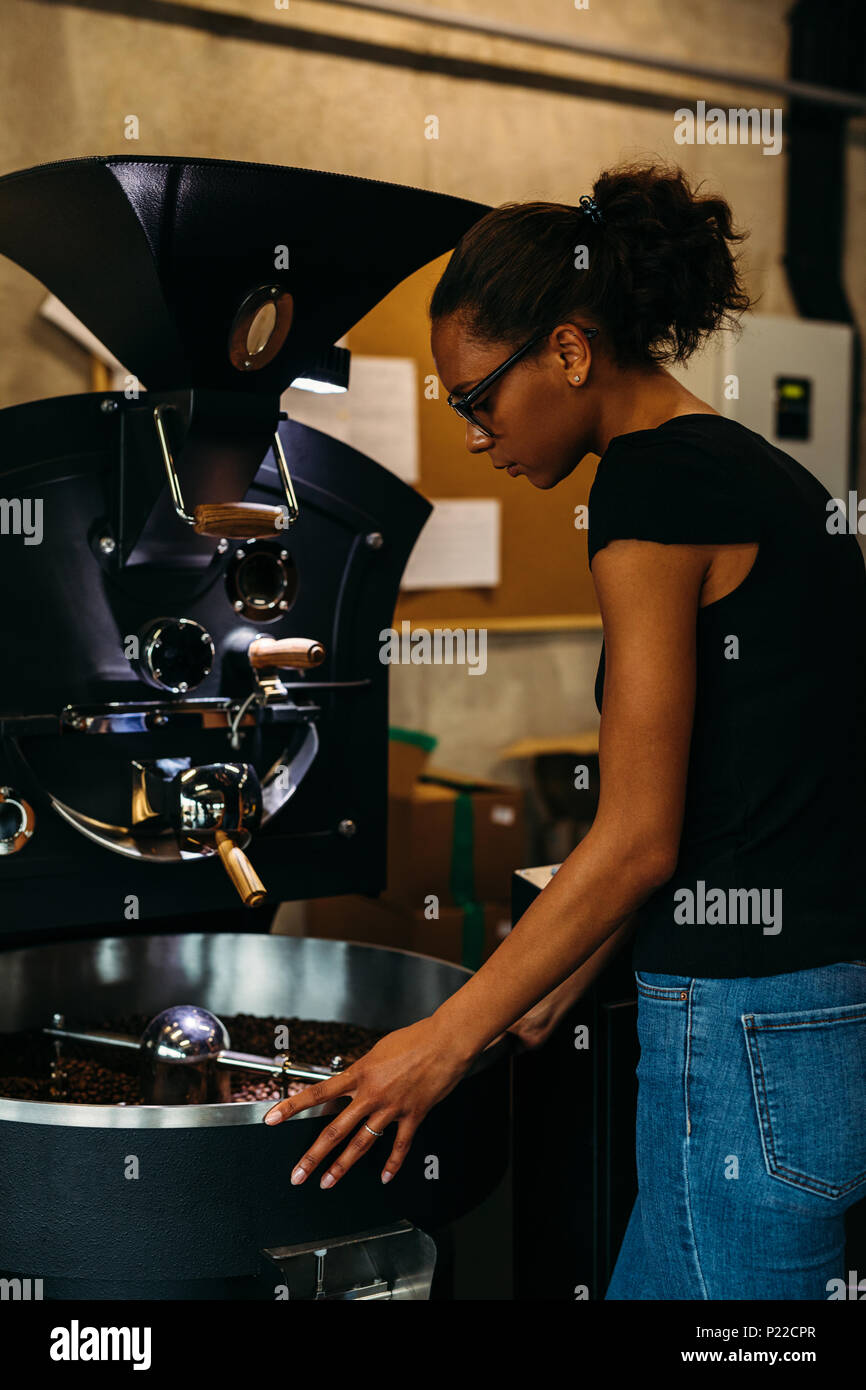 Weibliche Unternehmer stehend an modernen coffee bean Röstmaschine Stockfoto