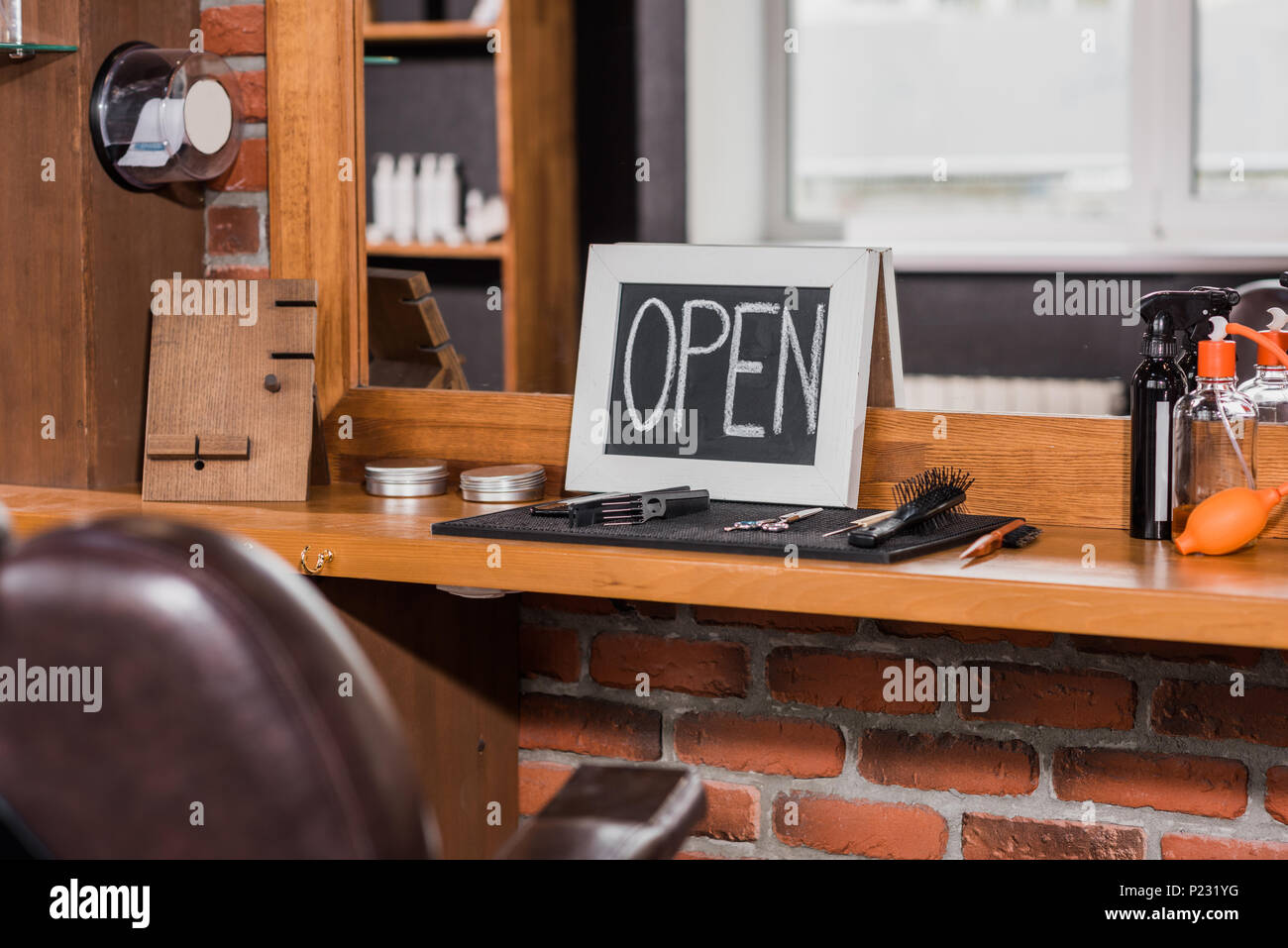 Tafel mit offenen Zeichen lehnte sich auf Spiegel an Barbershop Stockfoto