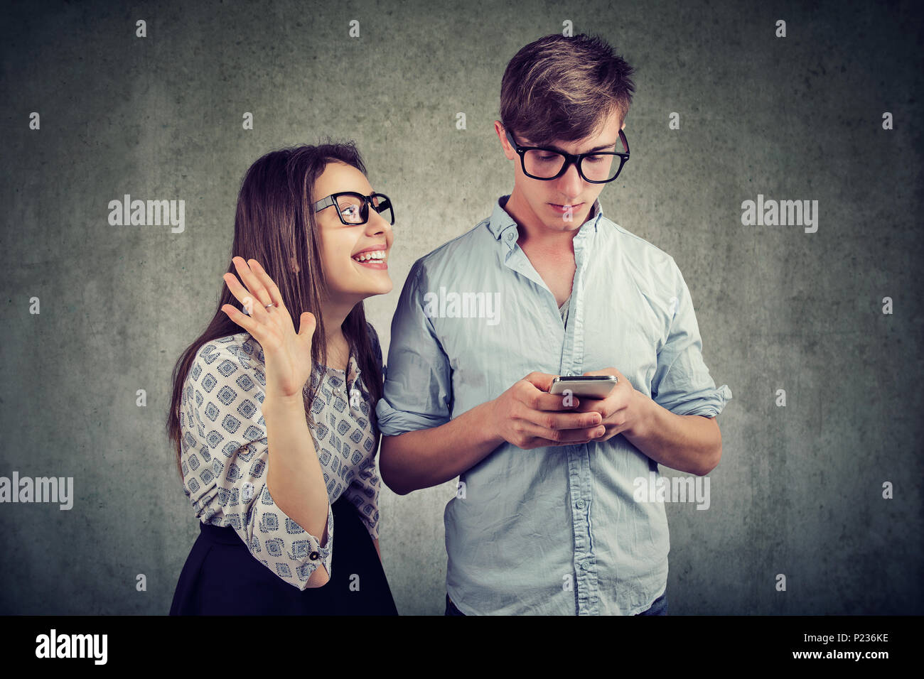 Attraktive Frau, die versucht, die Aufmerksamkeit der jungen gutaussehenden Mann sie ignorieren mit einem Smartphone im Internet surfen zu bringen. Telefon sucht Konzept. Stockfoto