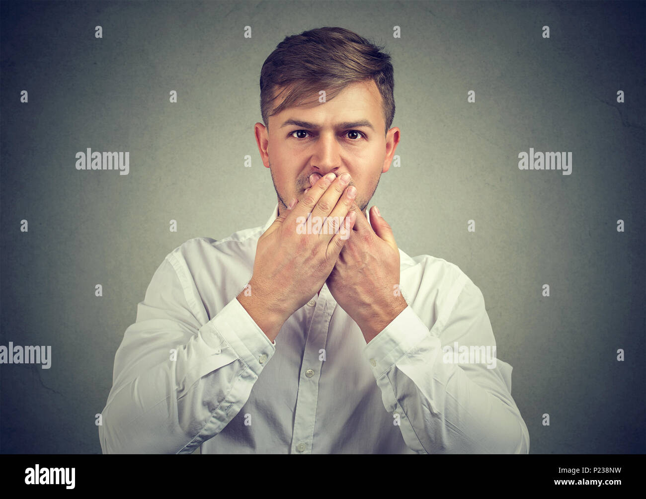 Junger Mann in weißem Hemd, Mund mit den Händen versuchen weniger zu sprechen und mit Kamera. Stockfoto