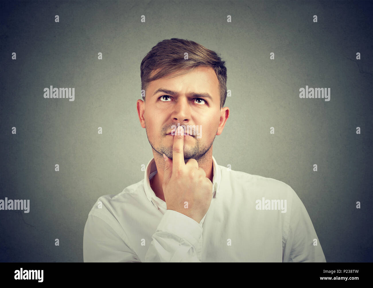 Stattliche legerer Mann im weißen Hemd berühren Lippen mit Finger und Denken auf Problem suchen. Stockfoto