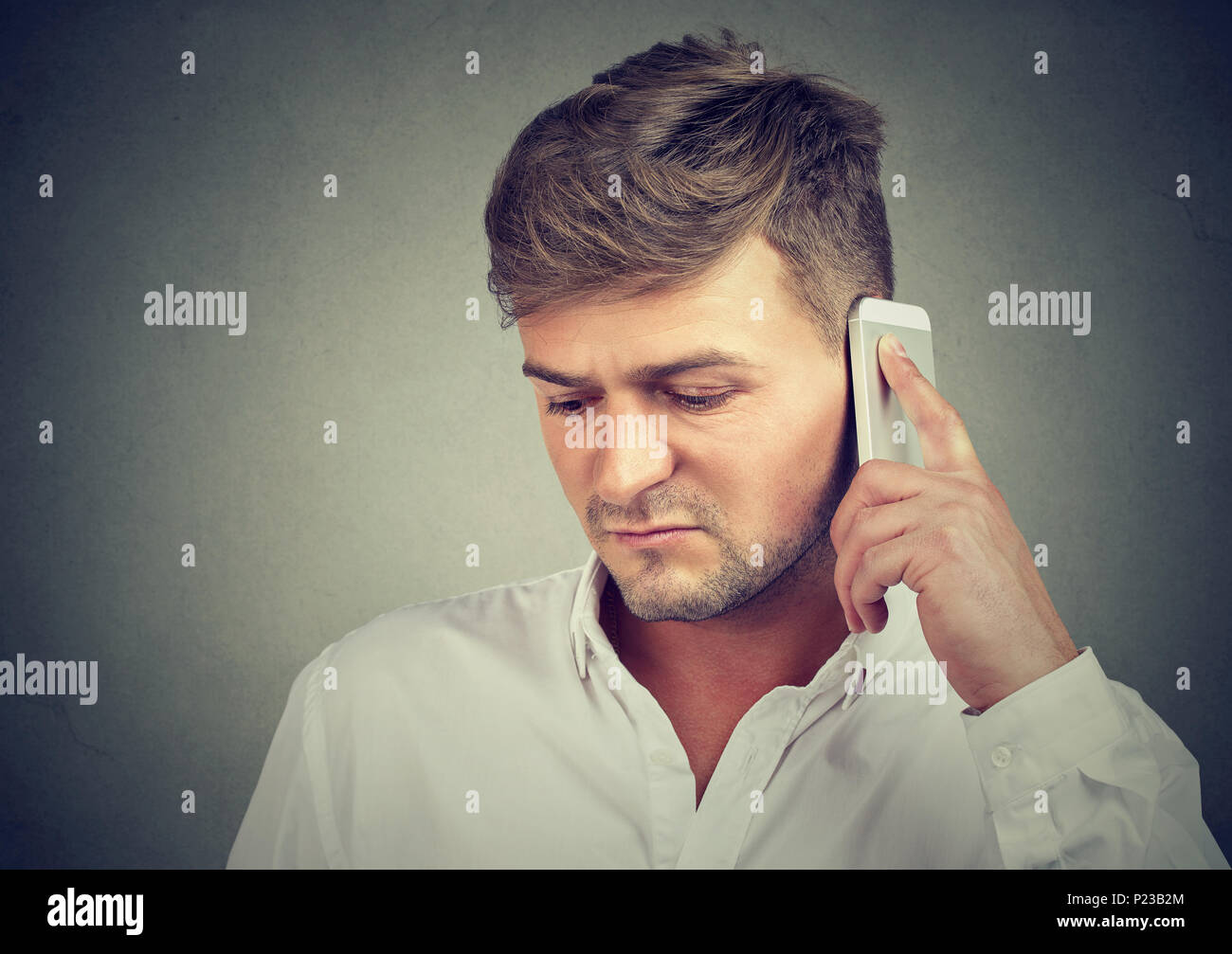 Junge unglückliche Menschen in Depression sprechen am Telefon und mit schlechten Nachrichten auf grauen Hintergrund. Stockfoto