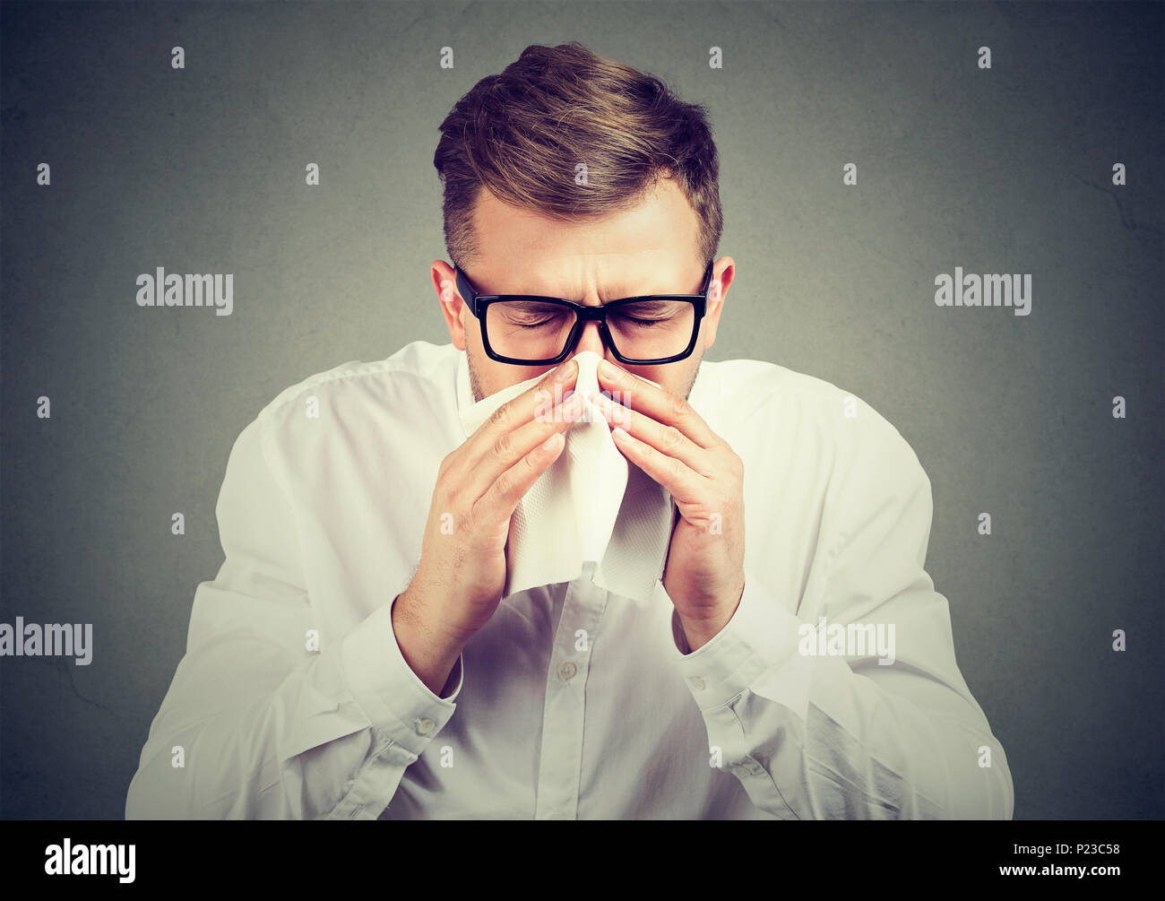 Junger Mann in Brillen Niesen in Taschentuch in kalten und Leiden von Virus. Stockfoto