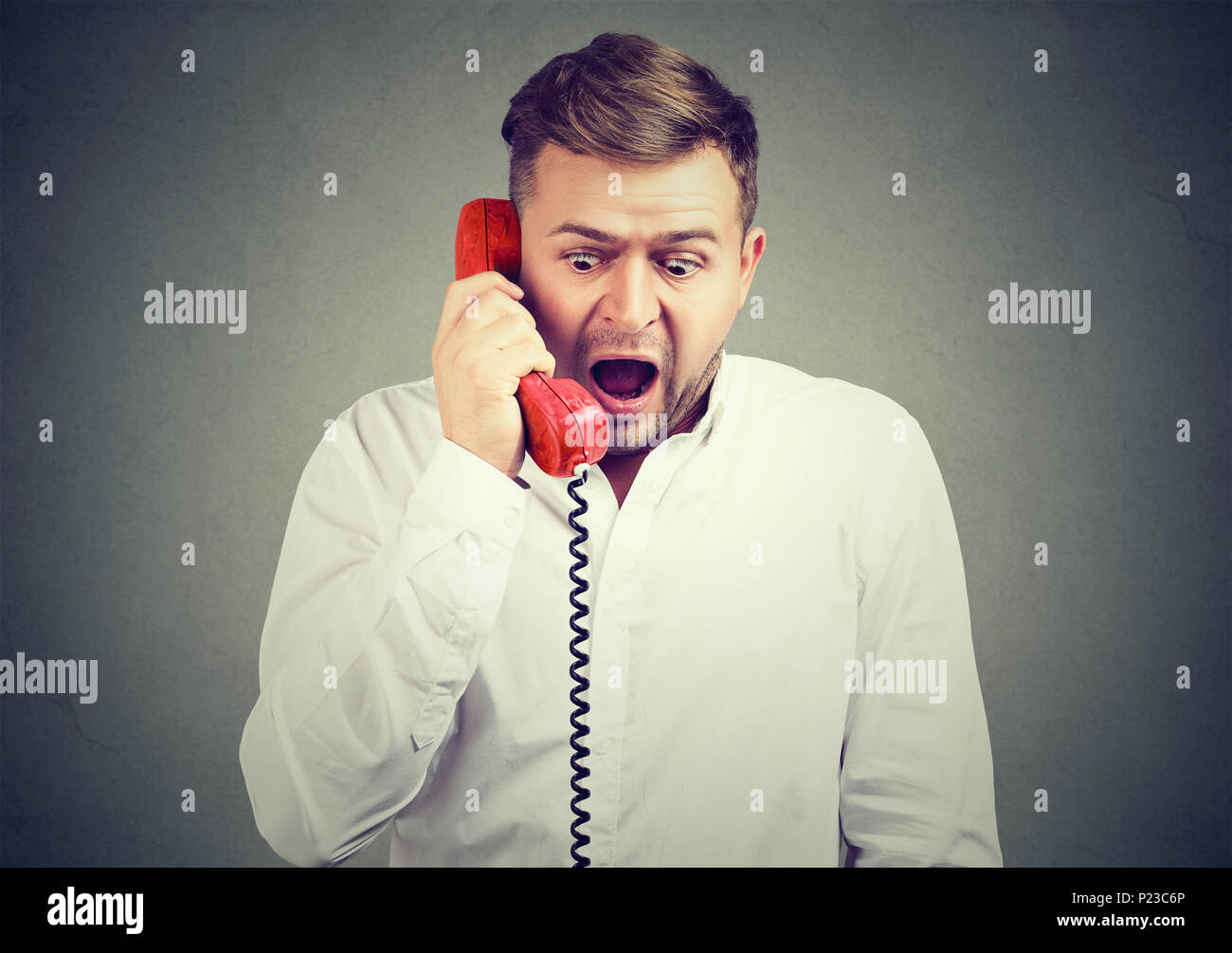 Expressive schreienden Mann sprechen auf einem Telefon betäubt, mit schlechten Nachrichten und reagieren. Stockfoto