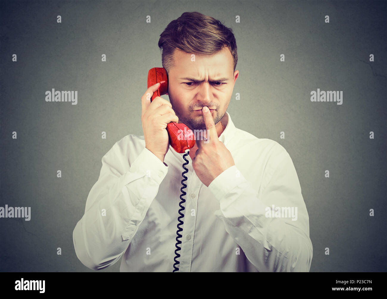Nachdenklicher Mann im weißen Hemd sprechen am Telefon und berühren Lippen in Zweifel in verwirrende Nachrichten. Stockfoto