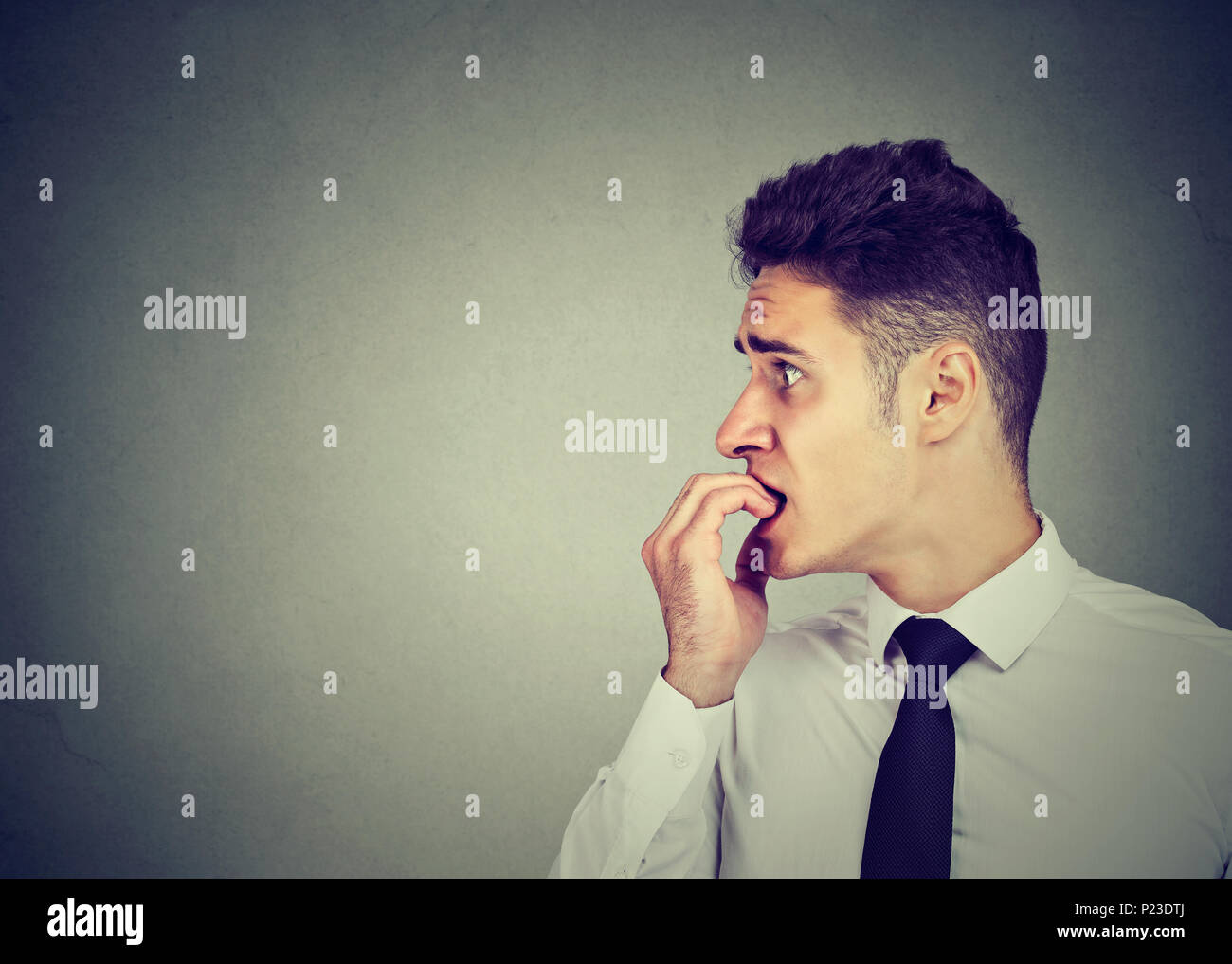 In dem Bestreben, junge Mann seine Fingernägel beißen auf die Seite schauen Beschäftigt Stockfoto