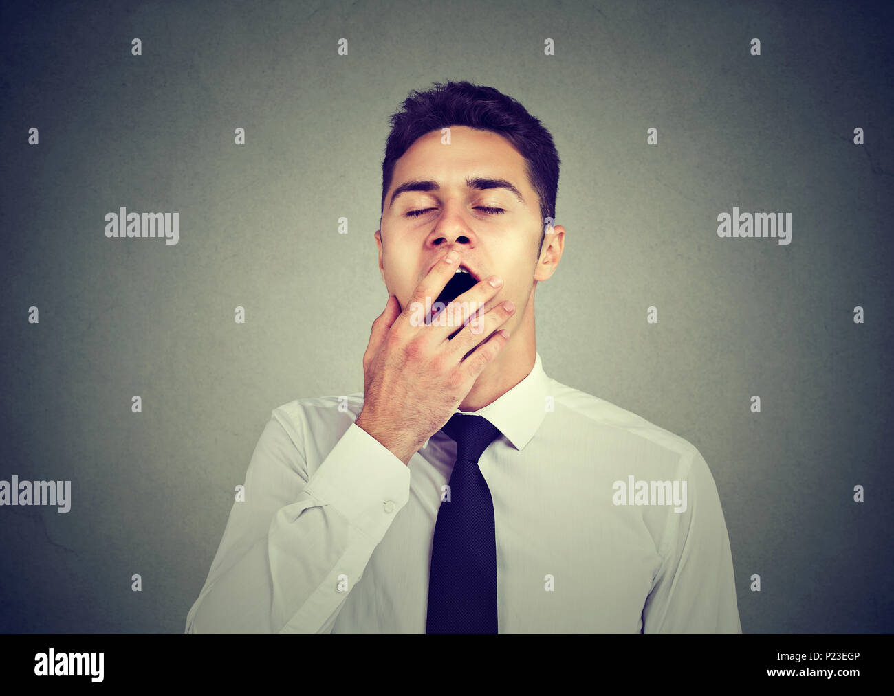 Verschlafene junge Mann gähnen mit der Hand über den Mund Stockfoto