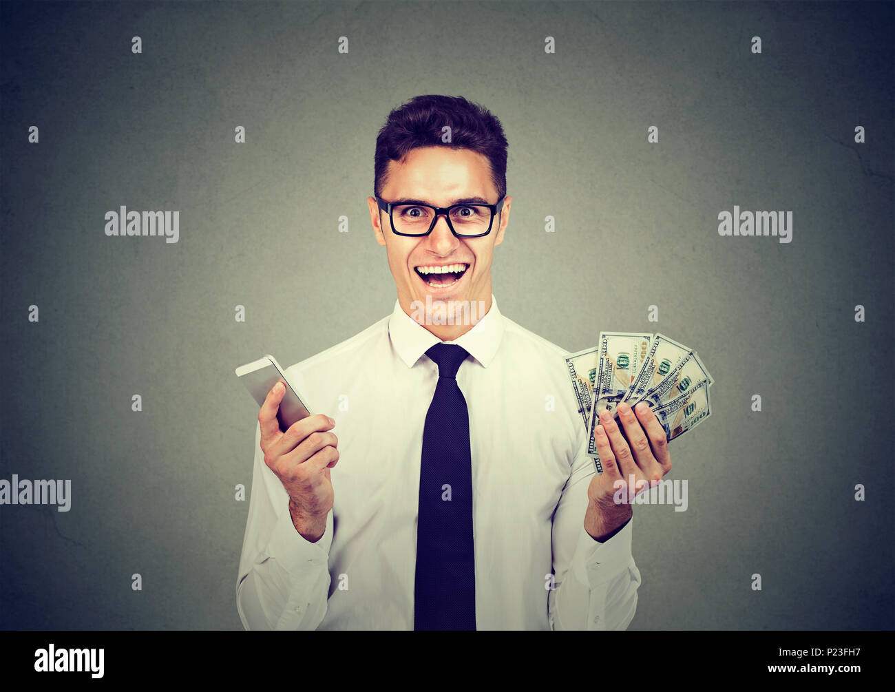 Aufgeregt happy Young Professional Geschäftsmann holding Handy und Geld Dollar cash Stockfoto