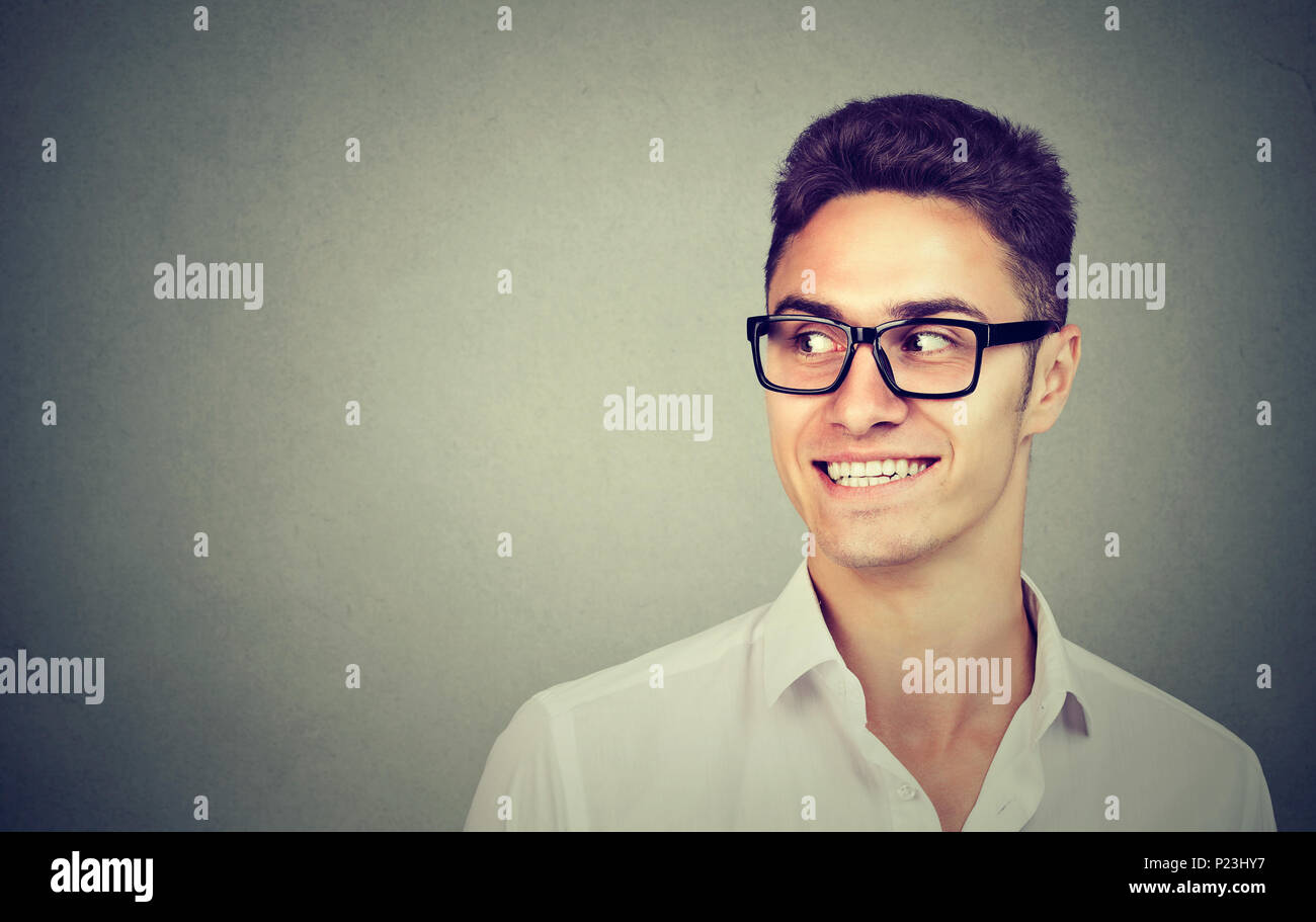 Lächelnd neugierig Mann seitlich auf grauem Hintergrund mit Kopie Raum suchen isoliert. Menschliche Emotionen Stockfoto