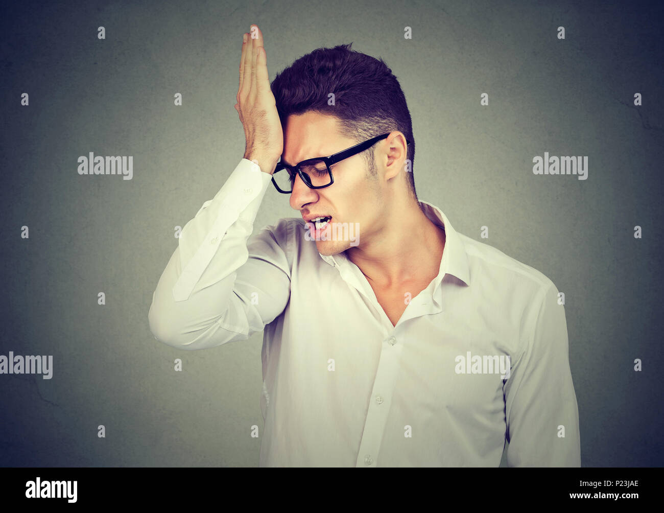 Mann, Slapping hand auf Kopf bedauert auf grauem Hintergrund. Negative menschliche Emotion Gefühl Stockfoto