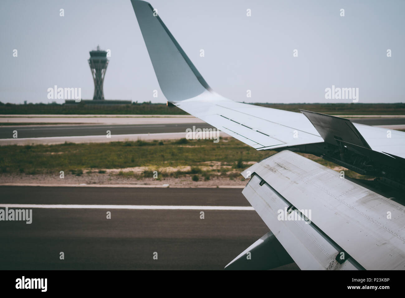 Flügel eines Flugzeugs öffnen Hinterkantenklappen während der Landung. Flughafen Turm im Hintergrund Stockfoto