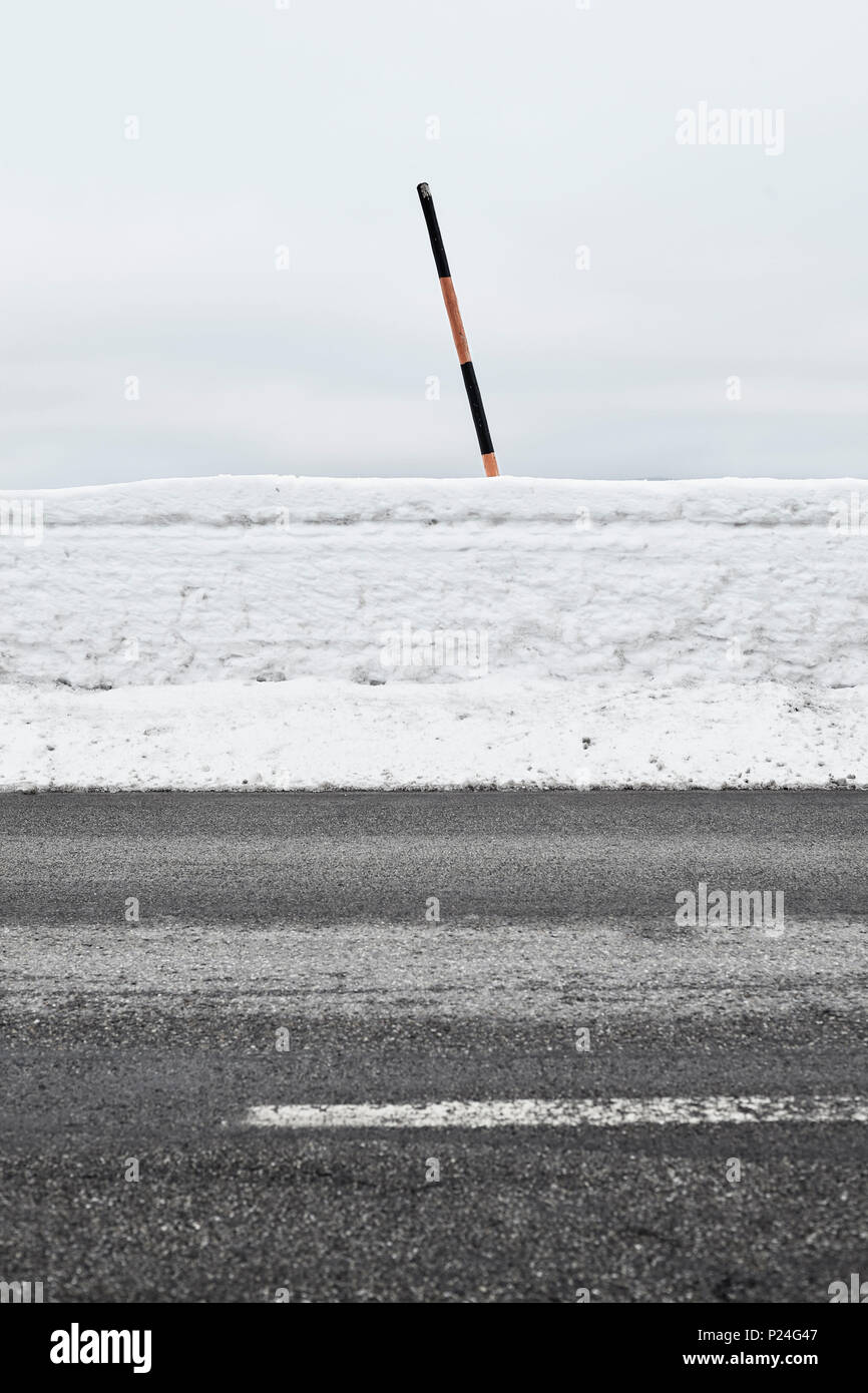Schiefe Pole im Schnee auf einer Landstraße im Winter, Wand aus Schnee Stockfoto