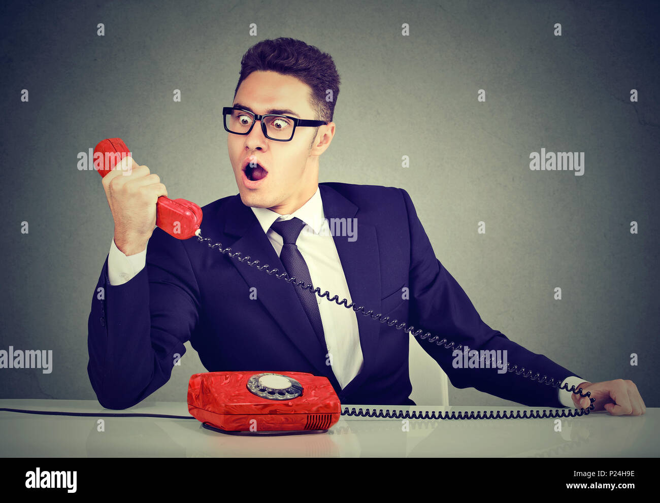 Young Business Mann empfängt fehlerhafte Nachrichten auf dem Telefon am Schreibtisch sitzt in seinem Büro Schockiert Stockfoto